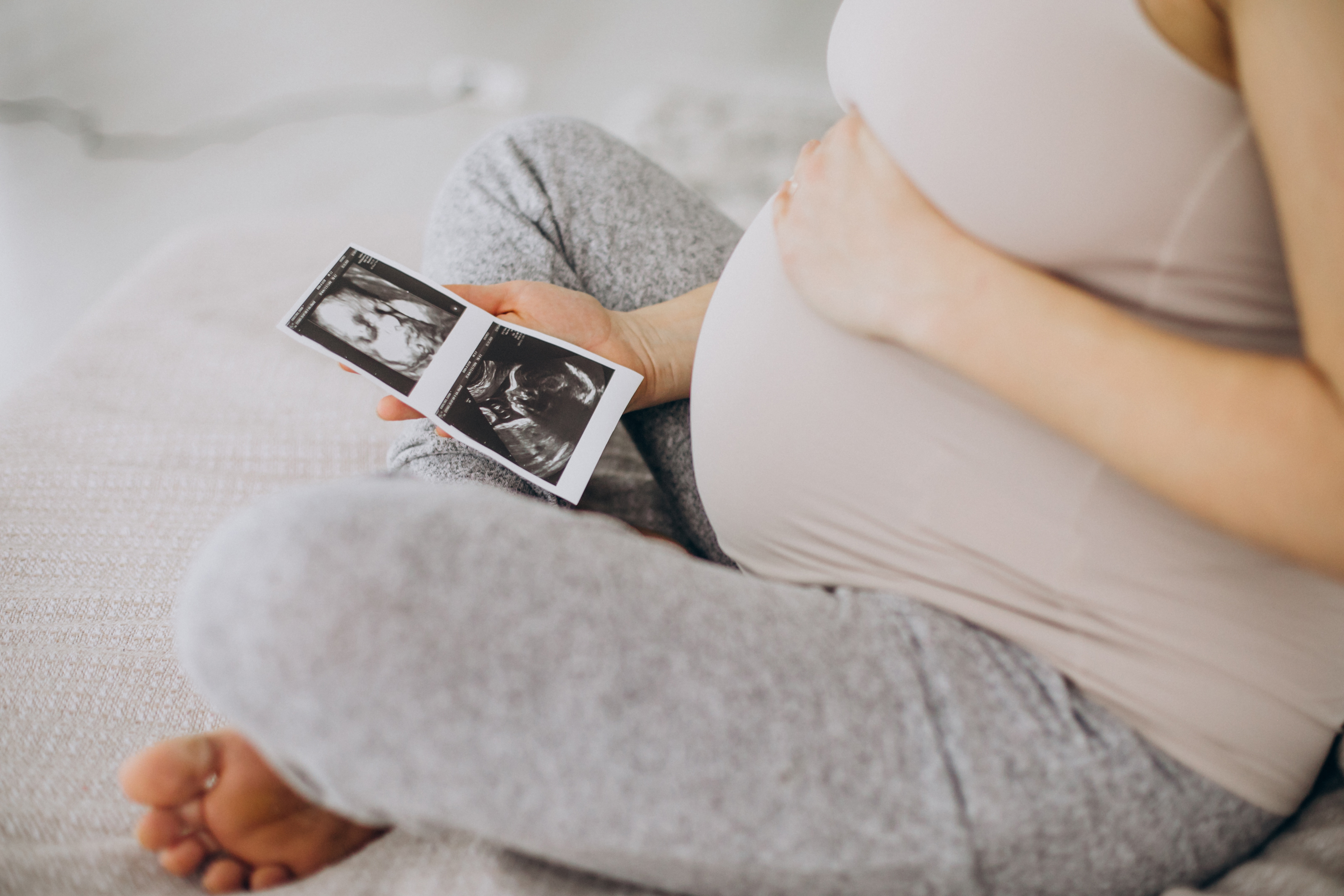 Mujer embarazada con foto de ultrasonido en la cama
